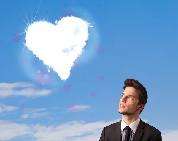 Handsome man looking at white heart cloud on blue sky — Stock Photo, Image