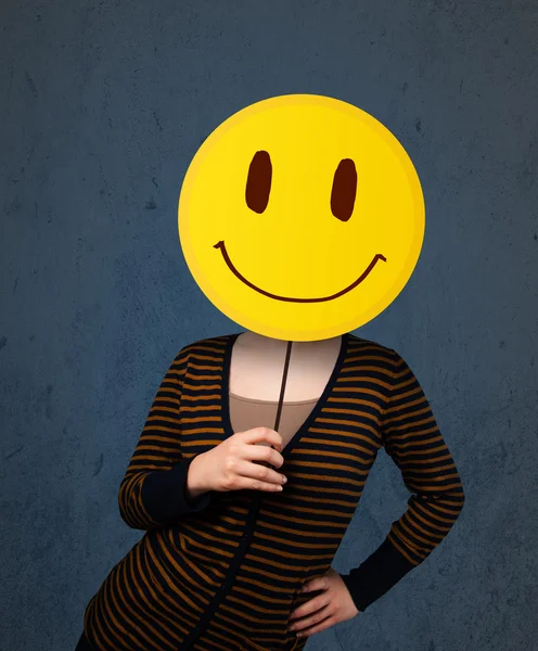 Mujer joven sosteniendo un emoticono sonriente —  Fotos de Stock