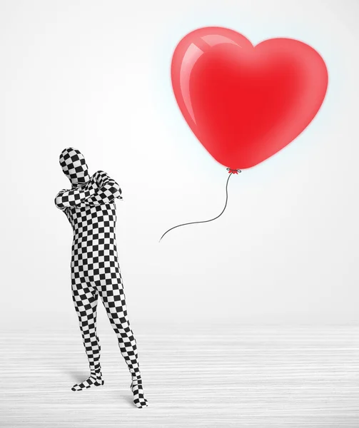 Leuke kerel in morpsuit body suit kijken naar een ballon vormige hart — Stockfoto
