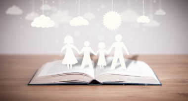 Ailenin karton figürleri açık bir kitabın üzerinde.