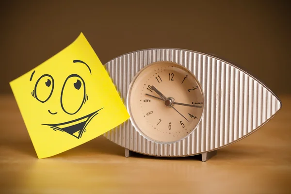 Post-it note with smiley face sticked on a clock — Stock Photo, Image