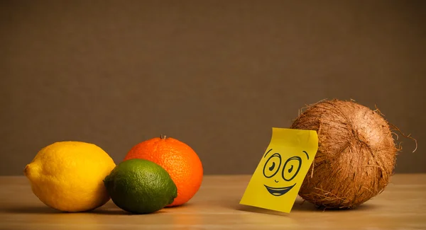 Coconut with post-it note watching at citrus fruits — Stock Photo, Image