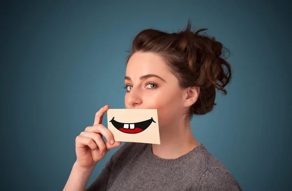 Feliz bonita mujer sosteniendo tarjeta con divertido smiley — Foto de Stock