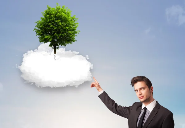 Joven señalando a un árbol verde en la parte superior de una nube blanca — Foto de Stock