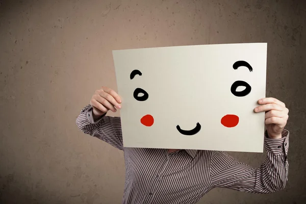 Businessman holding a cardboard with a smiley face on it — Stock Photo, Image