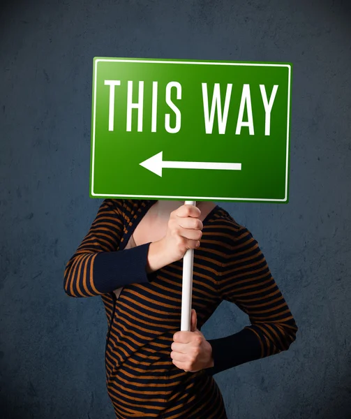 Young woman holding a direction sign — Stock Photo, Image