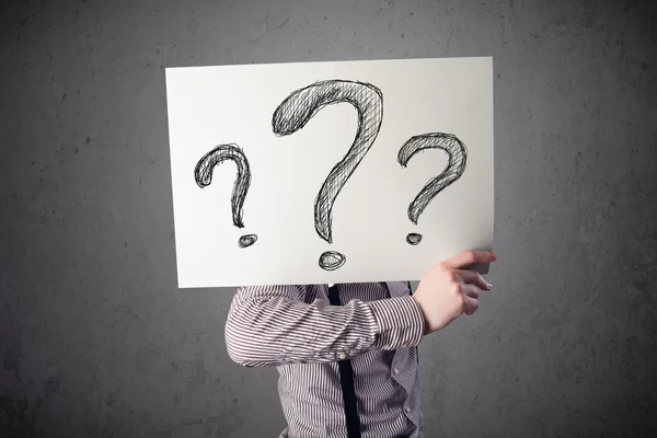 Businessman holding a paper with question marks in front of his — Stock Photo, Image