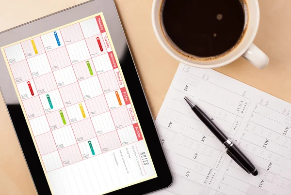 Tablet pc showing calendar on screen with a cup of coffee on a d — Stock Photo, Image
