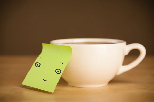 Nota post-it con la cara sonriente pegada en una taza — Foto de Stock