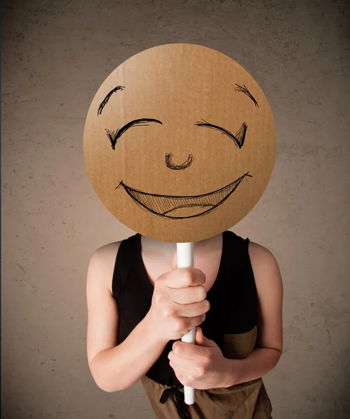 Jovem segurando uma placa de rosto sorridente — Fotografia de Stock