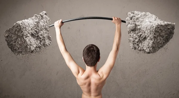 Skinny guy lifting large rock stone weights — Stock Photo, Image