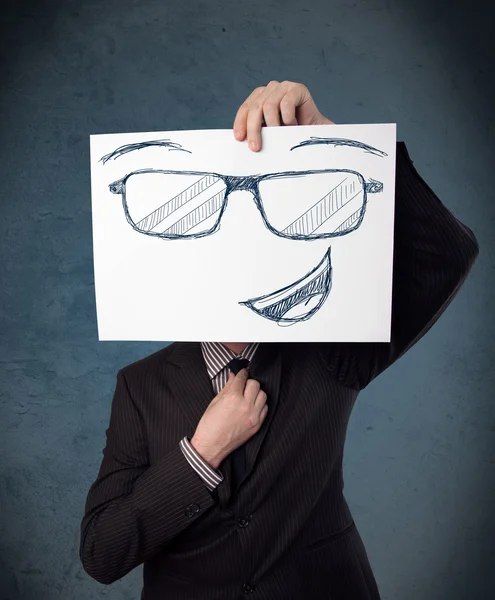 Businessman holding a paper with smiley face in front of his hea — Stock Photo, Image