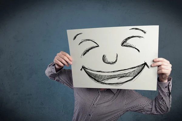 Empresário segurando um papel com rosto sorridente na frente de sua hea — Fotografia de Stock