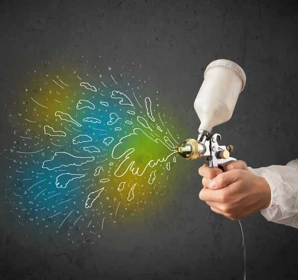 Worker with airbrush gun paints colorful lines and splashes — Stock Photo, Image