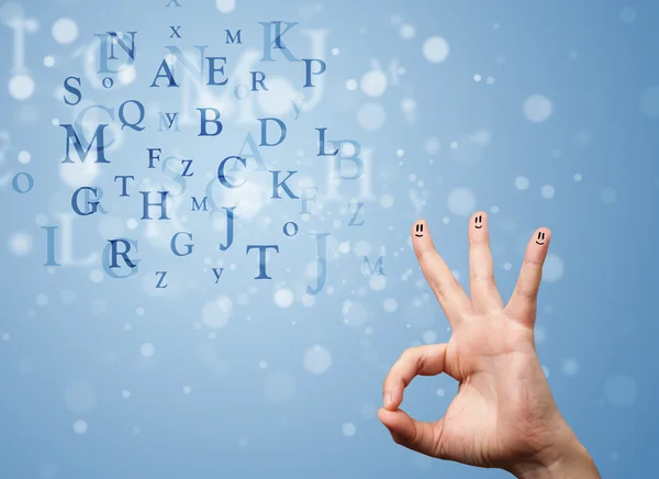 Happy smiley fingers looking at mixture of bokeh letters — Stock Photo, Image