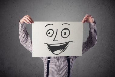 empresario sosteniendo una cartulina con cara sonriente en él en frente 