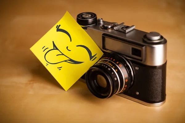 Post-it notera med smiley ansikte klistras på fotokamera — Stockfoto