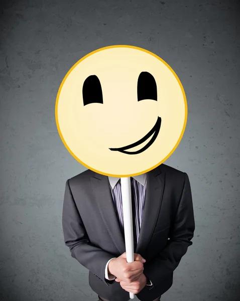 Empresario sosteniendo un emoticono sonriente — Foto de Stock