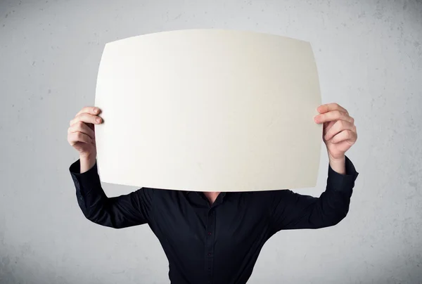 Businessman holding in front of his head a paper with copy space — Stock Photo, Image