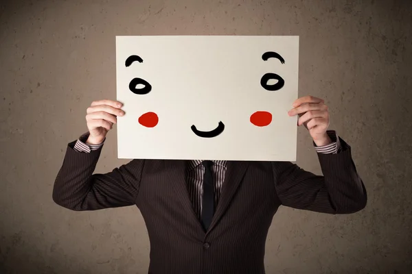 Zakenman houdt een karton met een smiley gezicht op het — Stockfoto