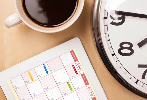 Tablet pc che mostra il calendario sullo schermo con una tazza di caffè su un d — Foto Stock