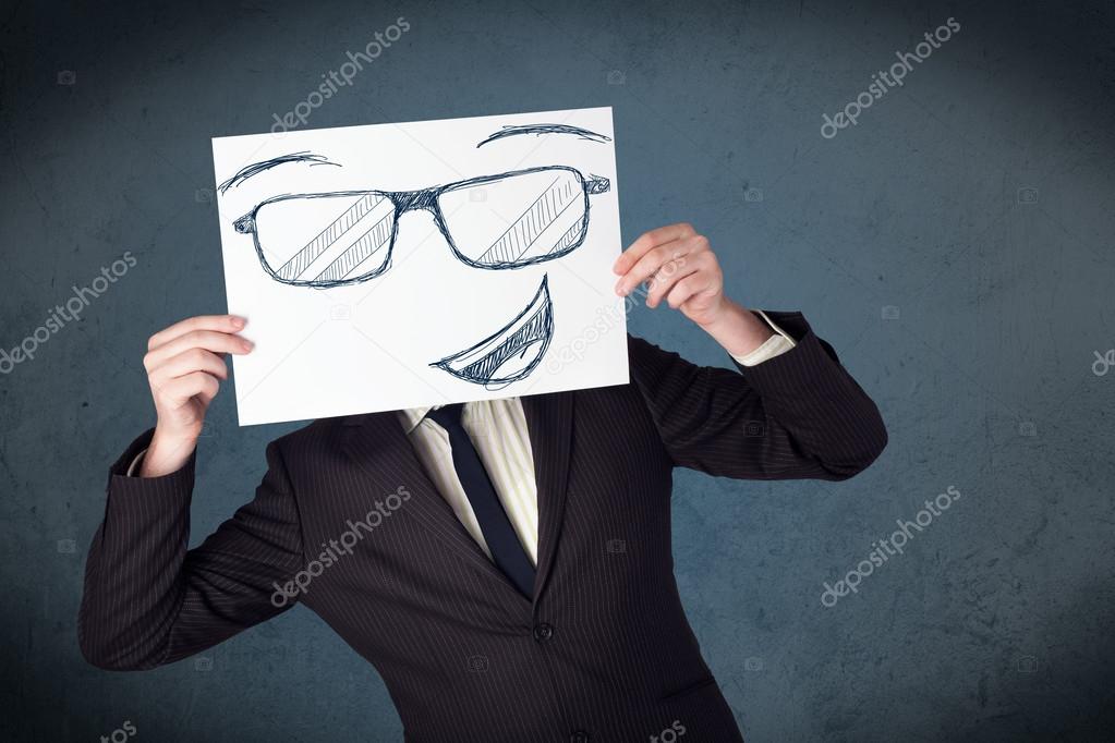 Businessman holding a paper with smiley face in front of his hea