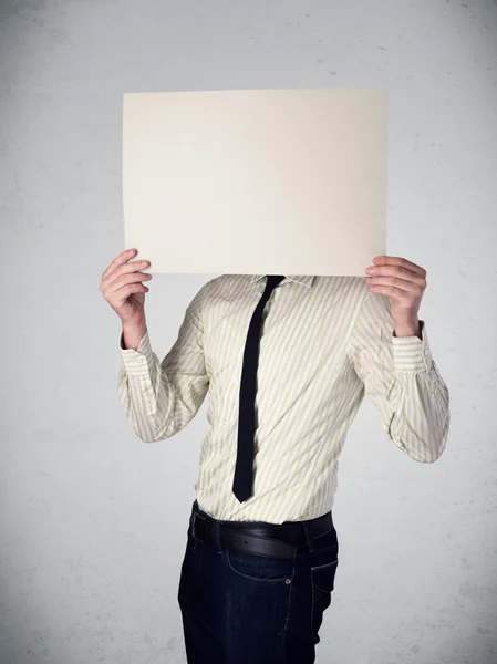 Businessman holding in front of his head a paper with copy space — Stock Photo, Image