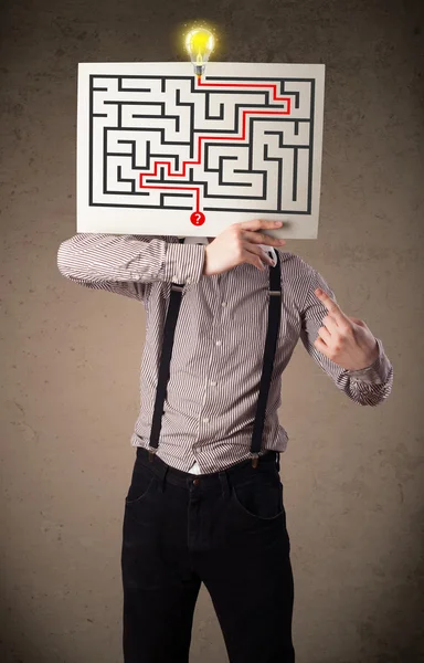 Businessman holding a paper with a labyrinth on it in front of h — Stock Photo, Image