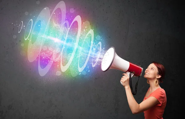 Young girl yells into a loudspeaker and colorful energy beam com — Stock Photo, Image