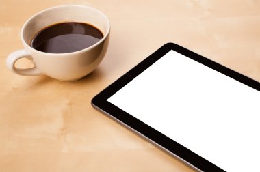 Boş alanı olan bir tablet bilgisayar ve masada bir fincan kahve.