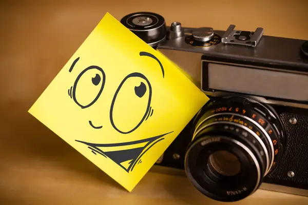 Post-it note with smiley face sticked on photo camera — Stock Photo, Image