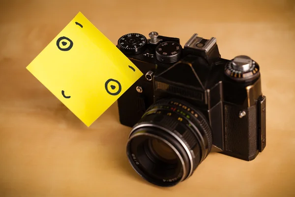 Post-it note with smiley face sticked on a photo camera — Stock Photo, Image