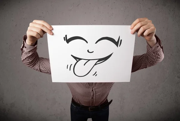 Businessman holding a paper with funny smiley face in front of h — Stock Photo, Image