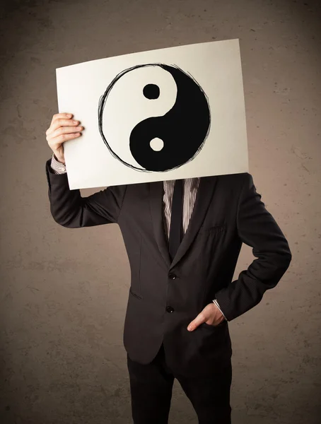 Businessman holding a paper with a yin-yang on it in front of hi — Stock Photo, Image
