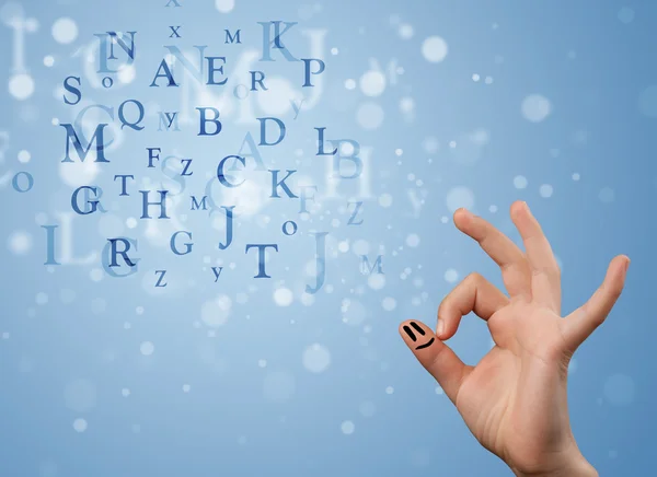 Happy smiley fingers looking at mixture of bokeh letters — Stock Photo, Image