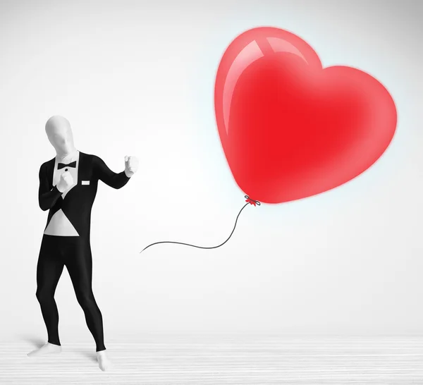 Симпатичний хлопець в костюмі для тіла дивиться на серце у формі повітряної кулі — стокове фото