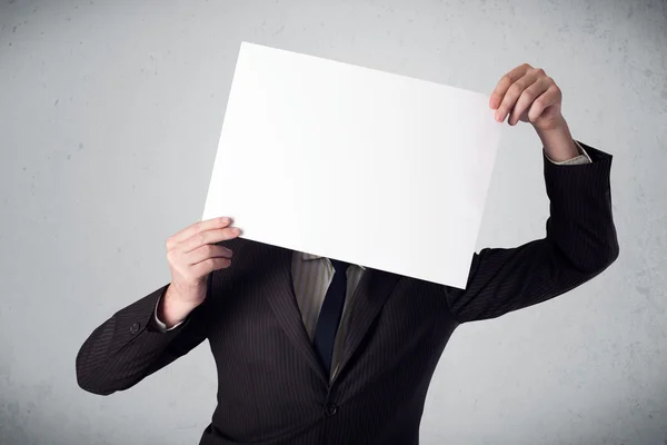 Businessman holding in front of his head a paper with copy space Royalty Free Stock Images