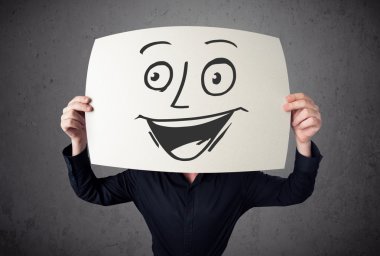 empresario sosteniendo una cartulina con cara sonriente en él en frente 