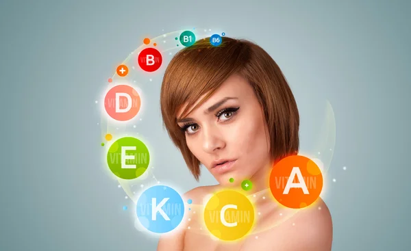 Hübsches junges Mädchen mit bunten Vitamin-Ikonen und Symbolen — Stockfoto