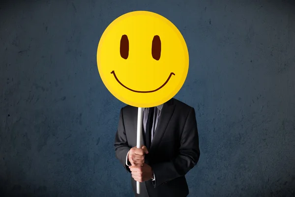 Empresario sosteniendo un emoticono sonriente —  Fotos de Stock