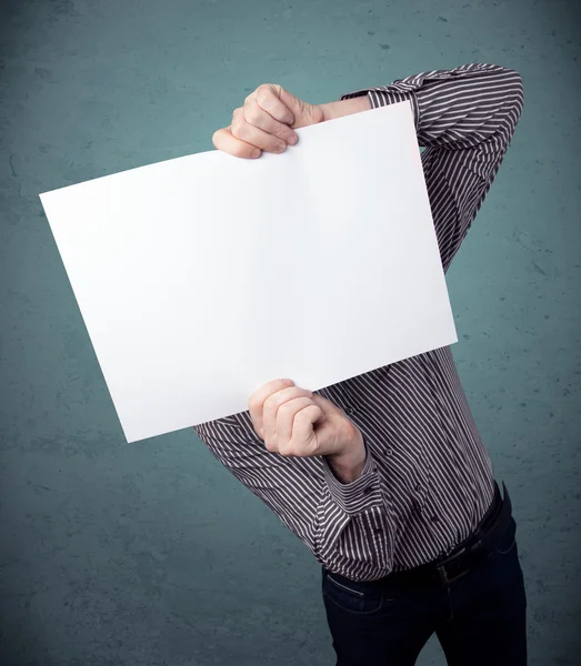 Uomo d'affari che tiene davanti alla testa un foglio con spazio per la copia — Foto Stock