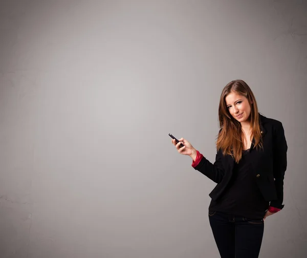 Young lady standing and holding a phone with copy space — Stock Photo, Image