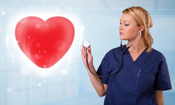 Young nurse healing a red heart — Stock Photo, Image