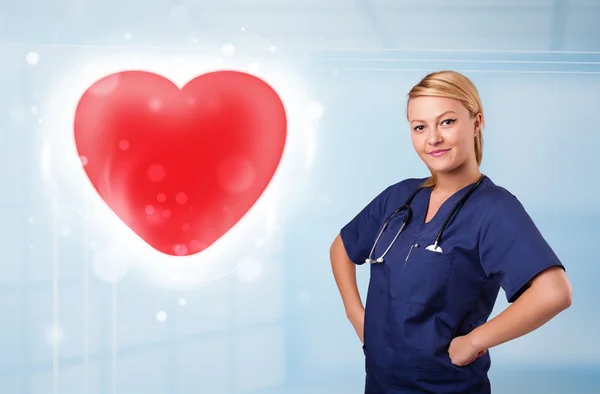 Young nurse healing a red heart — Stock Photo, Image