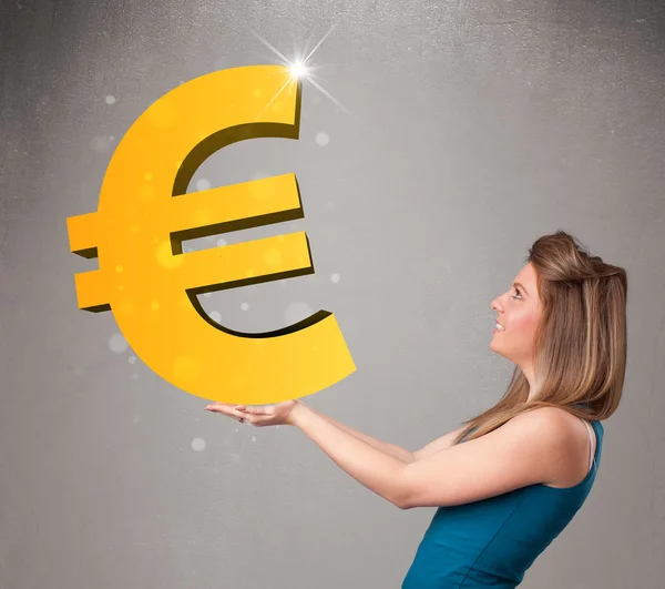 Beautiful girl holding a big 3d gold euro sign — Stock Photo, Image