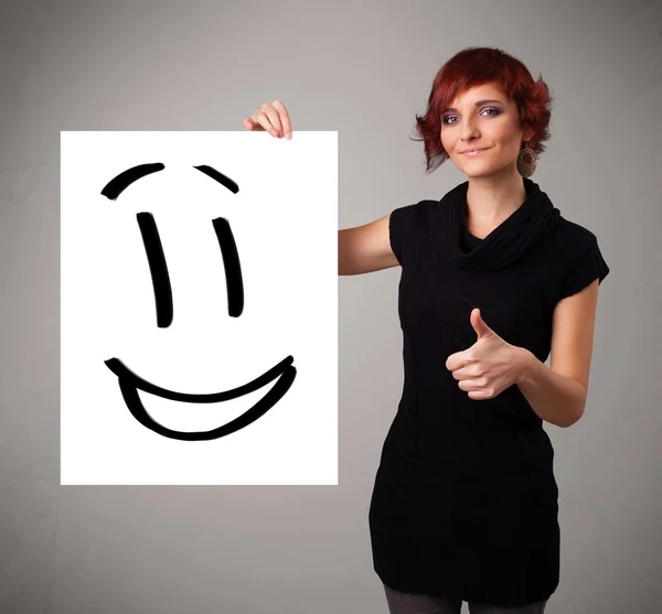 Fiatal nő gazdaság mosolygós arc rajz — Stock Fotó