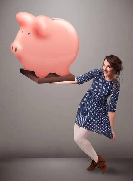 Jovem segurando uma enorme poupança porquinho banco — Fotografia de Stock