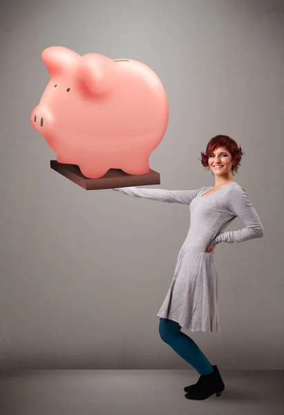 Jovem segurando uma enorme poupança porquinho banco — Fotografia de Stock