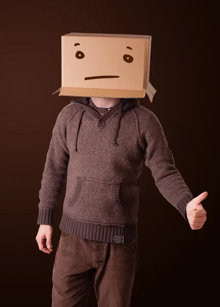 Young man gesturing with a cardboard box on his head with straig — Stock Photo, Image