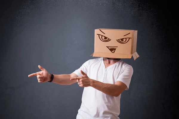 Young man gesturing with a cardboard box on his head with evil f — Stock Photo, Image